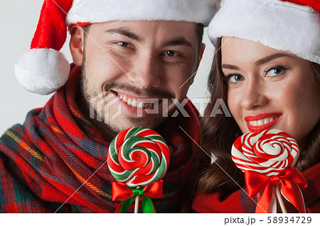 Couple in christmas santa hats with lollipops 58934729