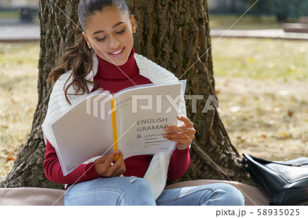 Smiling pretty student learning English grammar rules Smiling pretty student learning English grammar rules 58935025