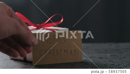 merry christmas paper card next to white gift box on terrazzo countertop 58937505