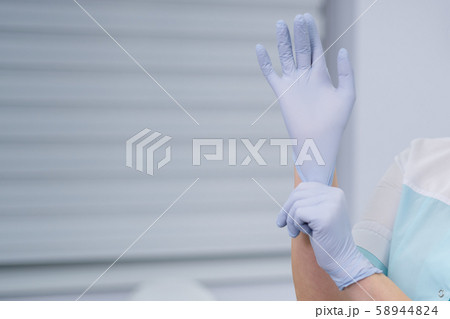 Blue gloves on a hand on a grey background 58944824