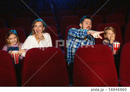 Young caucasian family watching a film at a movie theater Young caucasian family watching a film at a movie theater 58946860
