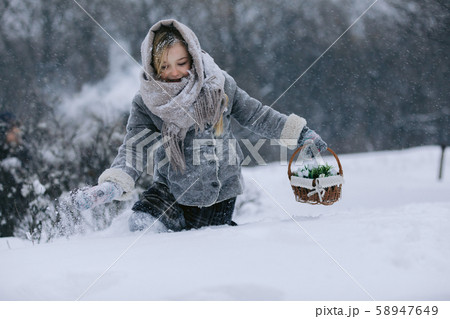 little girl with basket goes and looks for the first flowers under the snow in forest in winter 58947649