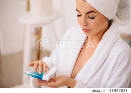 woman uses tonic or lotion product. 58947653