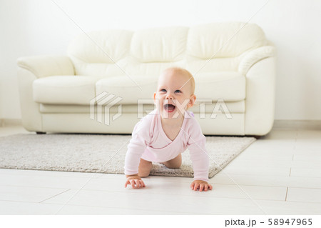 Portrait of a cute baby crawling and laughing on the floor at home Portrait of a cute baby crawling and laughing on the floor at home 58947965