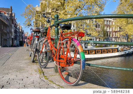 Orange bike with LGBT flag parked on a bridge in Amsterdam, Netherlands Orange bike with LGBT flag parked on a bridge in Amsterdam, Netherlands 58948238