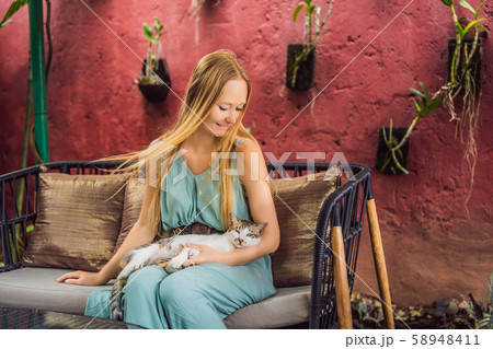 A young woman having a mediterranean breakfast seated at her sofa and with her cat 58948411