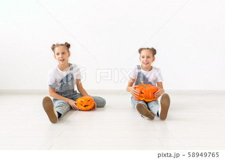 Happy Halloween, holidays and childhood concept - Cute little twins sisters girls with a pumpkins Happy Halloween, holidays and childhood concept - Cute little twins sisters girls with a pumpkins 58949765