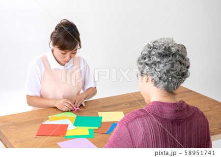 折り紙でレクリエーションする介護士と高齢者の女性 58951741