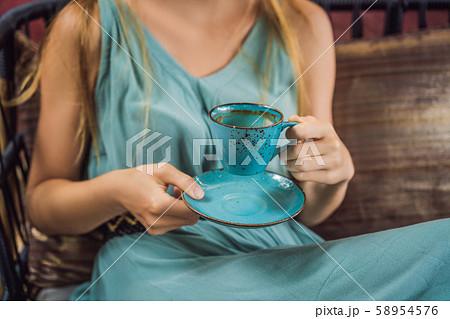 Young woman having a mediterranean breakfast seated at sofa and drinks hot aromatic coffee 58954576