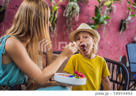Mother and son having a mediterranean breakfast seated at the sofa and eats Healthy tropical Mother and son having a mediterranean breakfast seated at the sofa and eats Healthy tropical 58954893