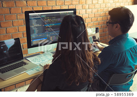 Two software developers are using computers to 58955369