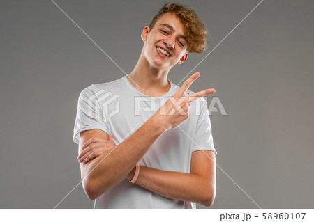 A portrait of young caucasian man with short red curly hair in white t-shirt show a piece isolated 58960107