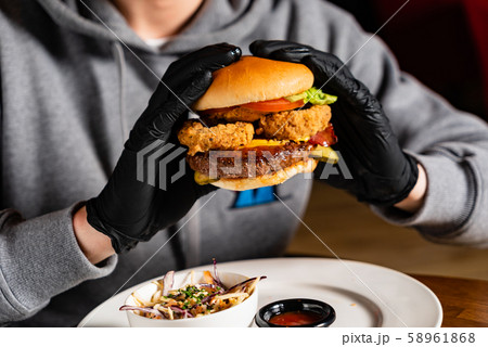 man in black gloves eating burger in the restaurant 58961868