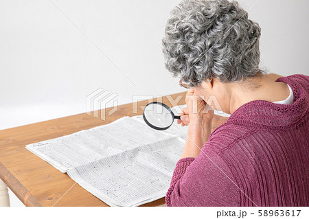 虫眼眼で新聞を読む高齢者の女性 虫眼眼で新聞を読む高齢者の女性 58963617