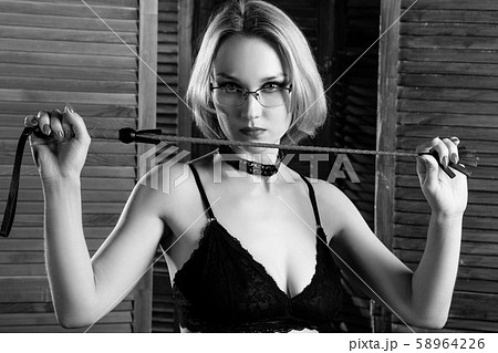 Sexy blond dominant woman holds whip over wooden folding panel Sexy blond dominant woman holds whip over wooden folding panel 58964226