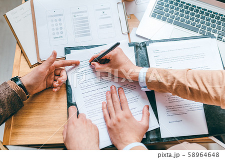 One of partners pointing at contract while his colleague putting personal data 58964648