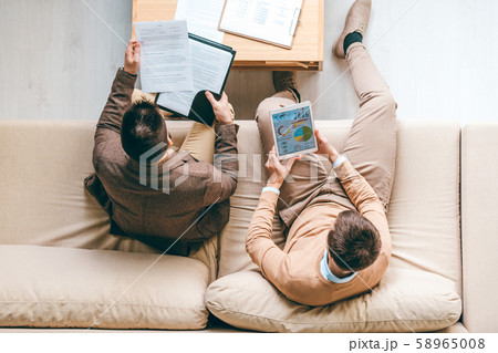 Two young male economists analyzing diagram and looking through financial papers 58965008