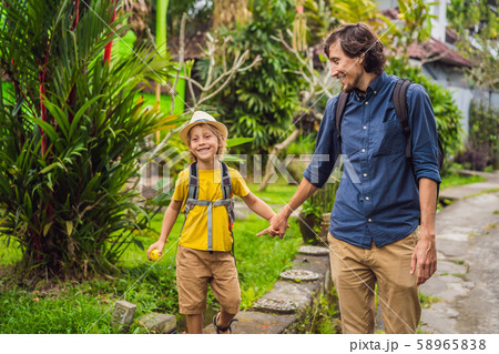 Father and son tourists in Bali walks along the narrow cozy streets of Ubud. Bali is a popular 58965838