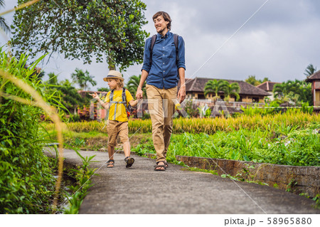 Father and son tourists in Bali walks along the narrow cozy streets of Ubud. Bali is a popular 58965880