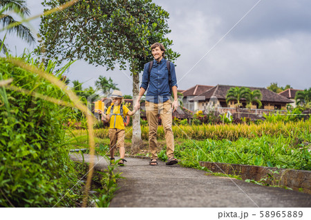 Father and son tourists in Bali walks along the narrow cozy streets of Ubud. Bali is a popular 58965889