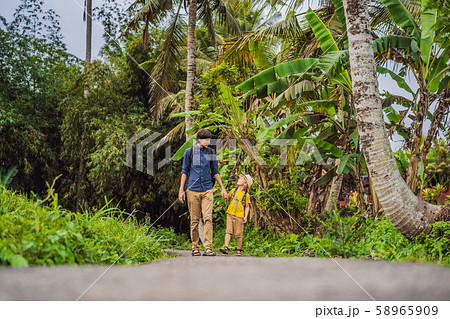 Father and son tourists in Bali walks along the narrow cozy streets of Ubud. Bali is a popular Father and son tourists in Bali walks along the narrow cozy streets of Ubud. Bali is a popular 58965909