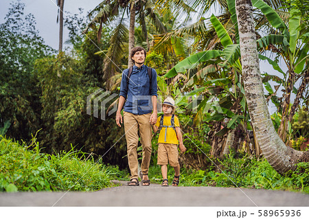 Father and son tourists in Bali walks along the narrow cozy streets of Ubud. Bali is a popular 58965936