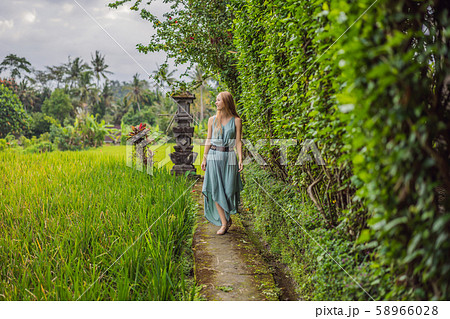 Young woman tourist in Bali walks along the narrow cozy streets of Ubud. Bali is a popular tourist 58966028