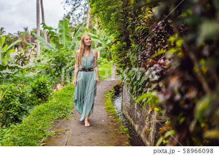 Young woman tourist in Bali walks along the narrow cozy streets of Ubud. Bali is a popular tourist 58966098