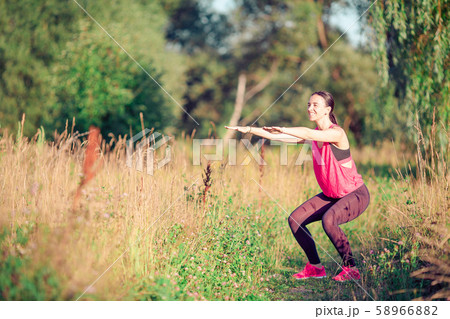 Young smiling woman doing sporty exercises outdoors Young smiling woman doing sporty exercises outdoors 58966882