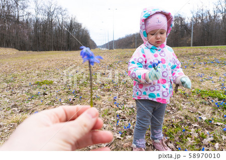 Woman holding blue snowdrop flower and little girl opposite 58970010