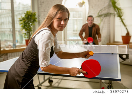 Young people playing table tennis in workplace, having fun Young people playing table tennis in workplace, having fun 58970273