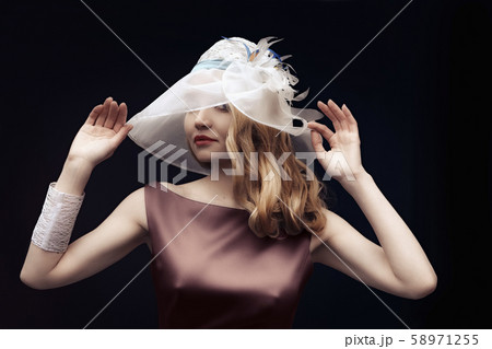 Beautiful lady in silk dress and wide hat posing Beautiful lady in silk dress and wide hat posing 58971255