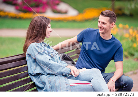 Relaxed young family on the bench in the park 58972573