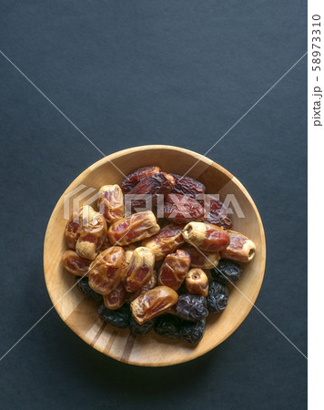 Dates in a wooden bowl on a black background. Dates in a wooden bowl on a black background. 58973310