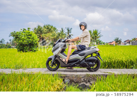 Male traveler on a bike among a rice field. Tourist travels to Bali Male traveler on a bike among a rice field. Tourist travels to Bali 58975294