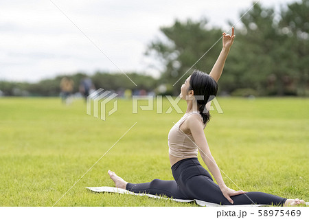 ヨガ 芝生公園でリラックス解放感 新体操のように柔らかい美しい体の女性の写真素材