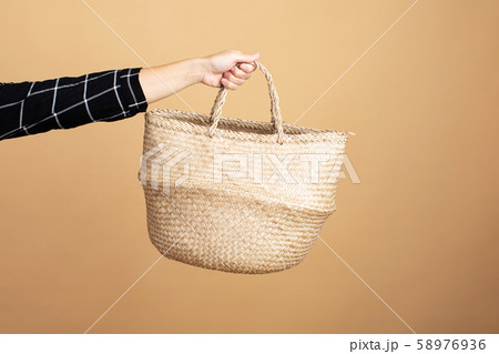 A young woman in a plaid dress stands with a wicker bag on an orange background A young woman in a plaid dress stands with a wicker bag on an orange background 58976936