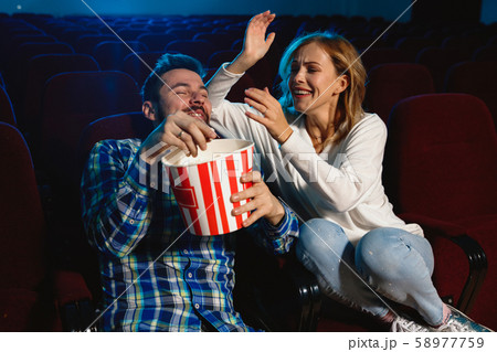 Attractive young caucasian couple watching a film at a movie theater Attractive young caucasian couple watching a film at a movie theater 58977759