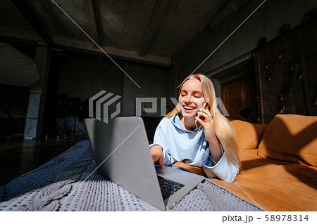 Smiling attractive woman lying on bed talking by smartphone Smiling attractive woman lying on bed talking by smartphone 58978314