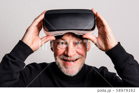 Portrait of a cheerful senior man with VR goggles in a studio. 58979162