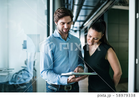 Young businesspeople with clipboard in an office, working. Young businesspeople with clipboard in an office, working. 58979338