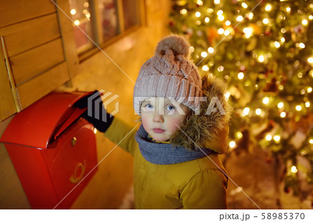 Little boy puts a letter for Santa Claus 58985370