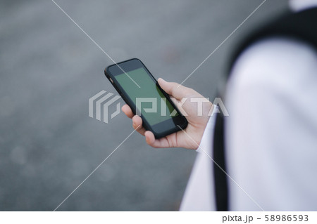 Mock up of teenage boy with wireless headphones use phone otside. Green screen 58986593