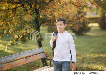 Schoolboy go to school in the morning. Happy teenager in white shirt with black backpack go to study 58986668