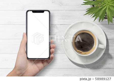スマートフォンを持つ手とコーヒーカップ 58989127
