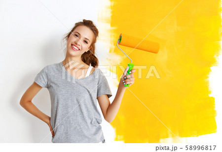 Repair in apartment. Happy young woman paints wall Repair in apartment. Happy young woman paints wall 58996817