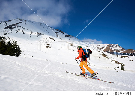 Skier tourist with backpack on background of bright blue sky and beautiful mountain panorama. 58997691