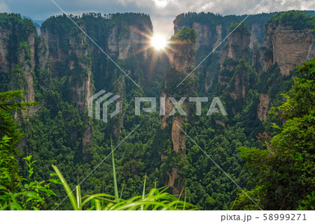 Sun shining through the vertical karst pillar rock 58999271