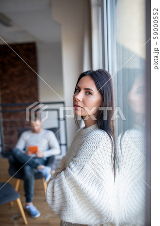Wife standing near window while husband working from home 59000552