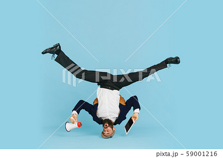 Businessman having fun dancing break dance on blue background at work 59001216